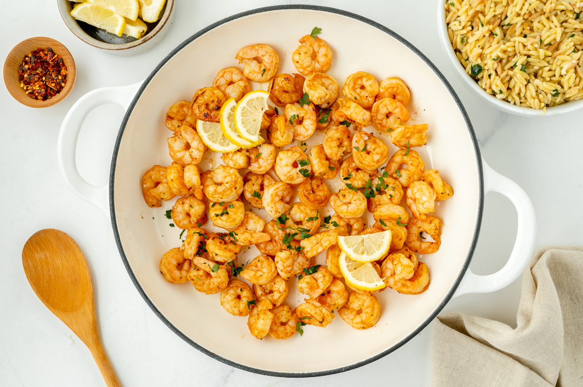 shrimp cooking in pan with lemon slices