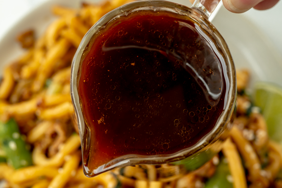 close up of udon noodle sauce pouring out of jar