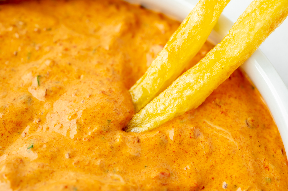 close up angled shot of two fries dipping into sauce
