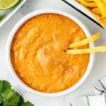 overhead shot of two fries in bowl of sauce