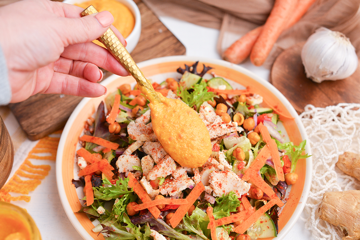 spoon adding dressing to salad