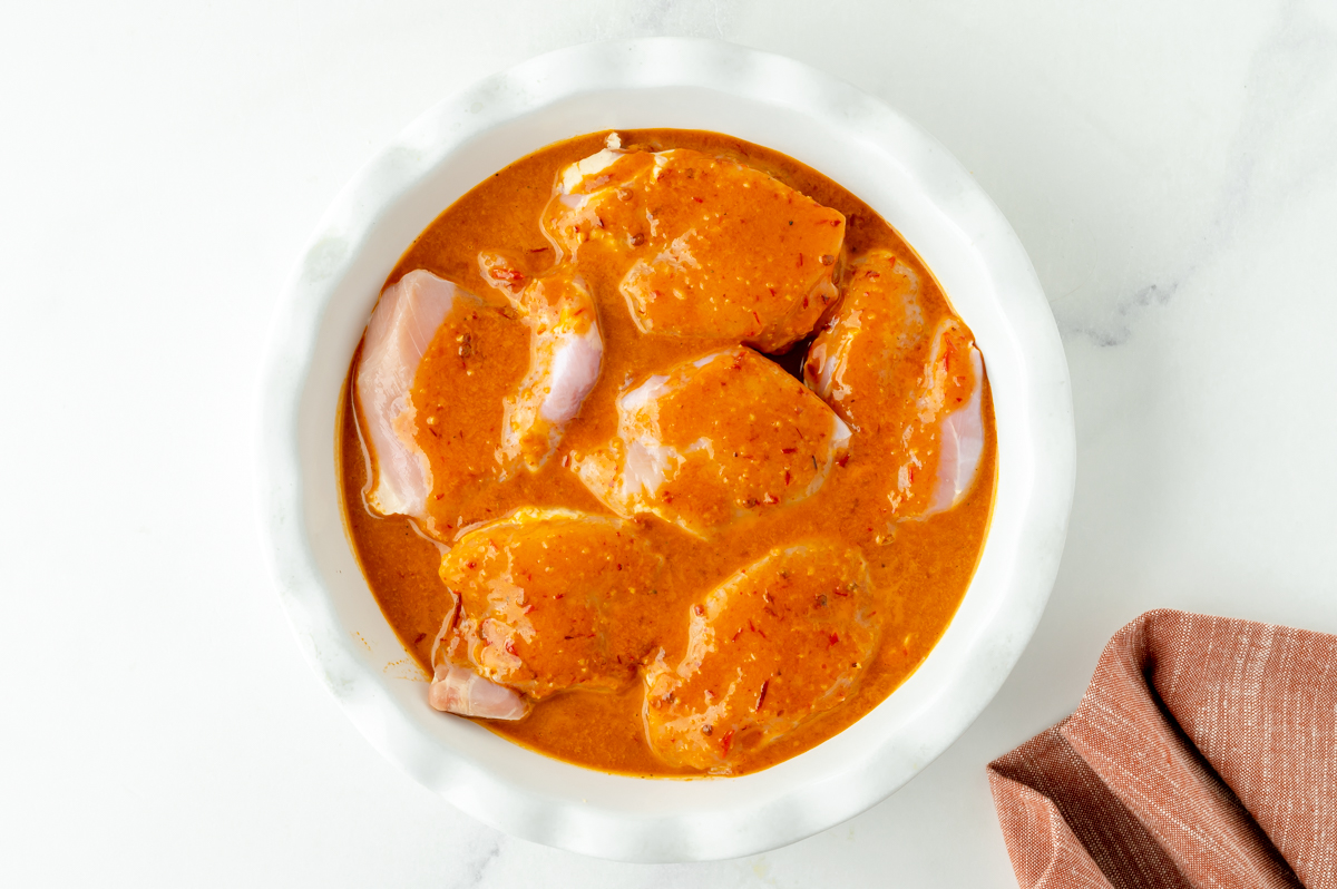 overhead shot of chicken thighs in bowl of marinade