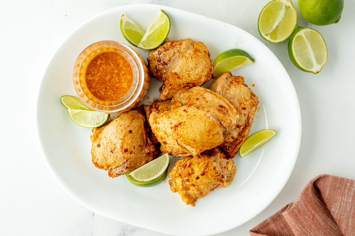 overhead shot of platter of chicken and limes with jar of marinade