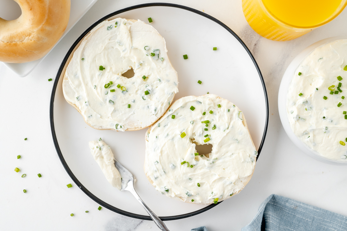 overhead shot of two bagel halves on plate smothered with cream cheese