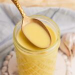 close up angled shot of spoon in jar of dressing