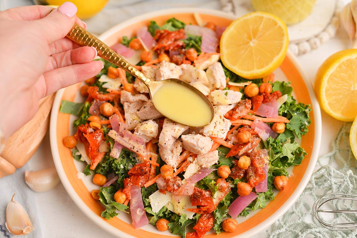 spoon adding dressing to salad