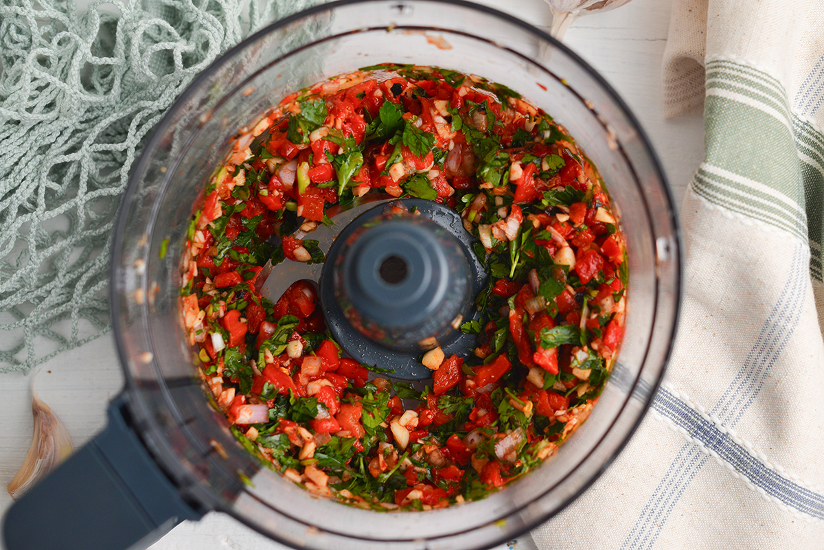 overhead shot of food processor with red chimichurri sauce ingredients