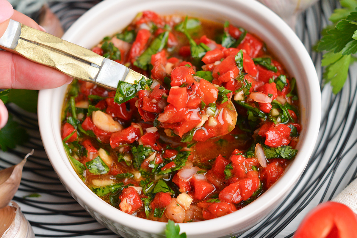 spoon in bowl of red chimichurri sauce