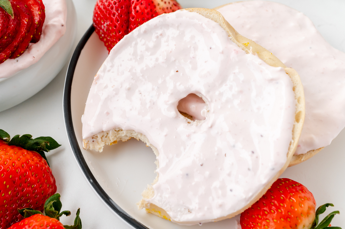 close up of fresh strawberry cream cheese on bagel with bite taken out